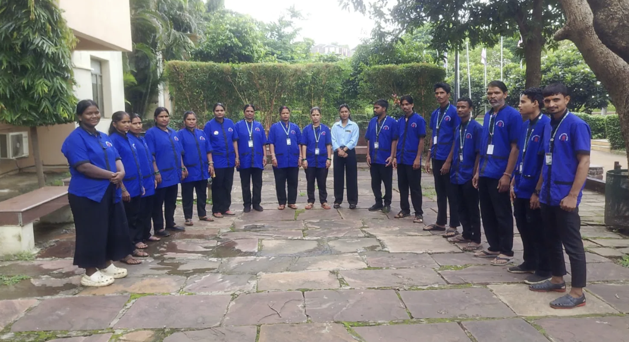 Supercare staff in blue uniforms standing in a semi-circle outdoors during a team briefing